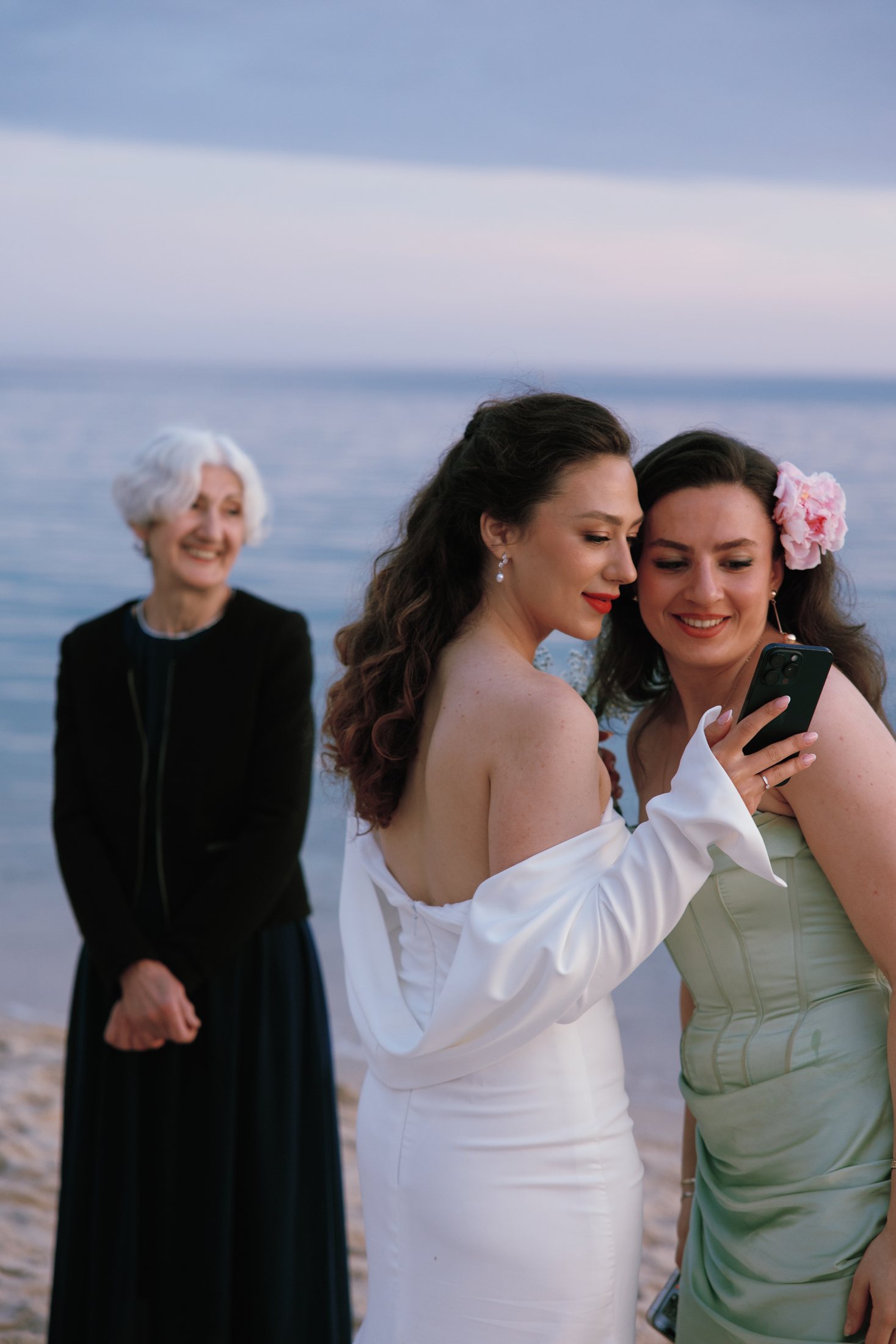 La mariée prend des photos avec ses parents et amis en regardant leurs téléphones portables sur le lieu du mariage